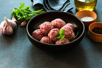 Raw ground meat meatballs in black bowl