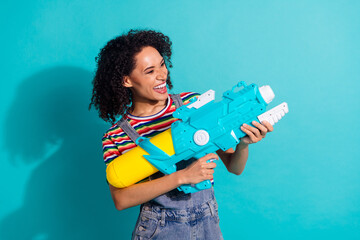 Photo of positive girl hold water gun shooting isolated cyan color background