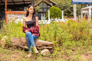 lifestyle: latin woman sitting on a log next to a poppy field