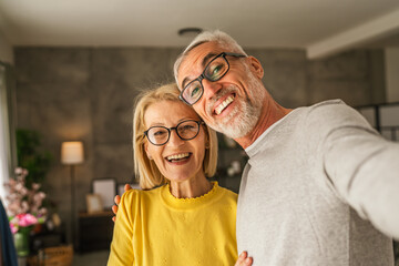 Mature senior husband and wife hold mobile phone and do self portrait