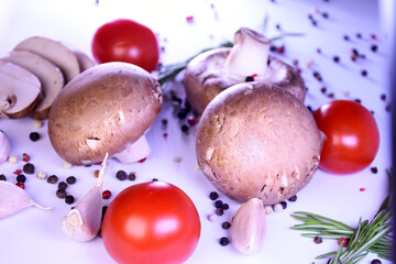 champignon mushrooms on a gray background with peppers and tomatoes. ingredients for a vegetarian dish