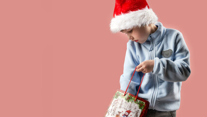 A child wearing a Santa Claus hat pulls a Christmas gift or purchase from a paper bag. The...