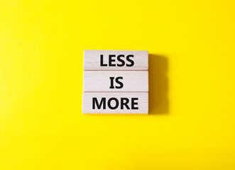 Less is More symbol. Concept words Less is More on wooden blocks. Beautiful yellow background. Business and Less is More concept. Copy space.