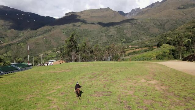 un joven y atractivo campesino montando un caballo caminando bajo la c&aacute;lida luz del sol durante el d&iacute;a. Concepto de viaje de estilo de vida saludable, turismo experiencial.rural,quechua,estilo de vida