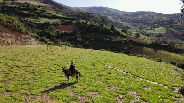 un joven y atractivo campesino montando un caballo caminando bajo la c&aacute;lida luz del sol durante el d&iacute;a. Concepto de viaje de estilo de vida saludable, turismo experiencial.rural,quechua,estilo de vida