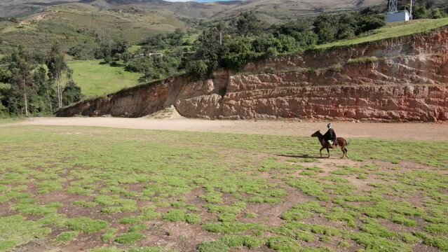 un joven y atractivo campesino montando un caballo caminando bajo la c&aacute;lida luz del sol durante el d&iacute;a. Concepto de viaje de estilo de vida saludable, turismo experiencial.rural,quechua,estilo de vida