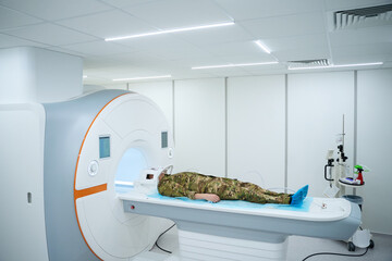 Military patient prepared for MRI of brain in scanning room
