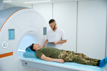 Radiographer preparing serviceperson for magnetic resonance imaging