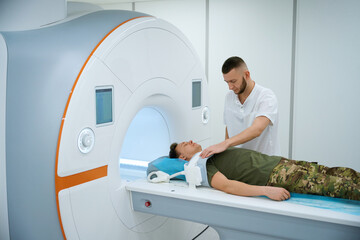 Radiographer is preparing serviceman for magnetic resonance imaging of shoulder