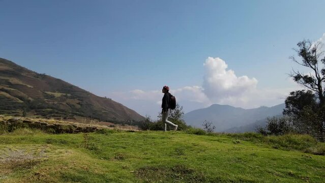 Mujer excursionista viajera caminando, aventurera con mochila sinti&eacute;ndose victoriosa frente a la monta&ntilde;a, al aire libre para la educaci&oacute;n de la naturaleza en vacaciones. Concepto de viaje,salto