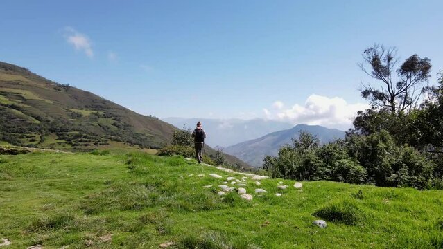 Hermosas monta&ntilde;as y hombre joven turista caminando con mochila en el camino en verano. Paisaje con turista en la cima de la monta&ntilde;a, bosque, colinas, cielo blancos con nubes, Viaje,quechua,sierra