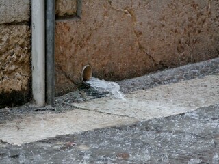 Wasser strömt aus Wasserrohr auf Straße bei Starkregen