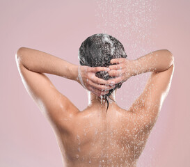 Woman, hair and back or washing in studio, pink background and cleansing with shampoo or model under water. Grooming, hygiene and female person wet for self care, showering foam and wellness routine
