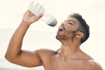 Beach, fitness and man drinking water for hydration, thirsty and wellness for health. Outdoor, male...