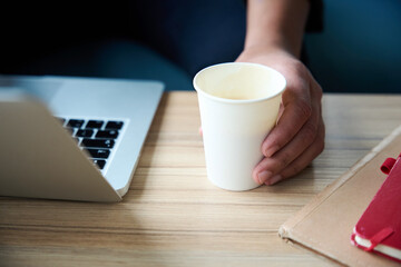 Hand holding paper glass which standing on table