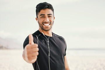 Fototapeta premium Happy, man and fitness with thumbs up and earphones for listening to music on run or beach workout. Smile, male person and hand for success gesture with victory or achievement in exercise goals