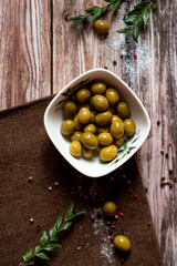 Green olives in a bowl stand on the table