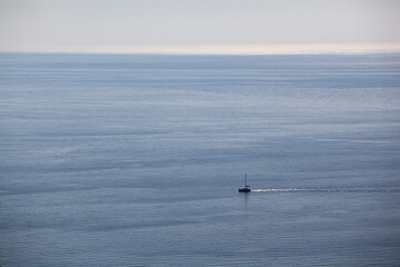 A small sailing boat sails on the sea surface of the Adriatic Sea. Balkans. View from above. Montenegro. Budva. Horizontal.