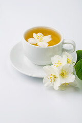 Cup with green tea and jasmine flowers on a white background.