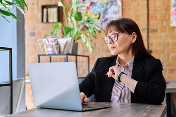Middle-aged business woman working remotely with laptop in coworking