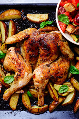 spatchcock chicken with potatoes on a baking sheet and panzanella salad..top veiw