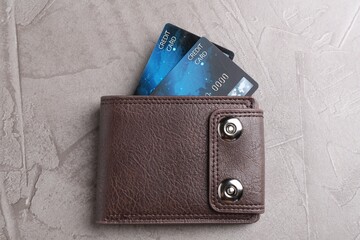 Credit cards in leather wallet on grey textured table, top view