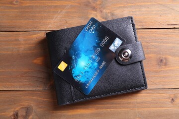 Credit card and leather wallet on wooden table, top view