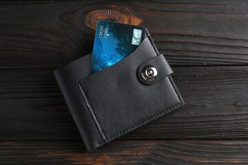 Credit card in leather wallet on wooden table, top view