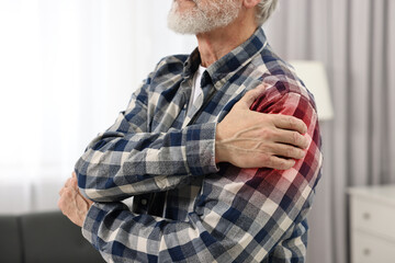 Senior man suffering from pain in shoulder indoors, closeup