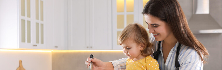 Mother and her little daughter cooking together in kitchen, space for text. Banner design