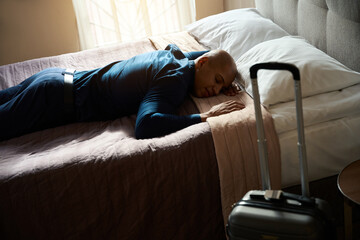 Tired african american businessman wearing formal wear sleeping on bed in hotel