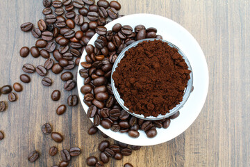 Roasted Coffee beans powder in a bowl with beans in a plate top view 