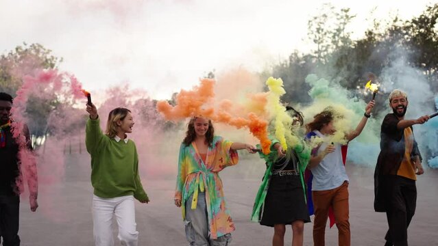 LGBT young people excited walking, jumping and dancing celebrating with rainbow colors smoke flares and flags gay pride outdoor. Inclusive relations and symbols in gen z community