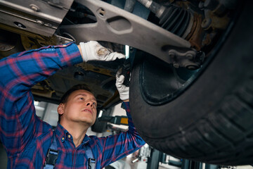 Man inspecting chassis in the car service center