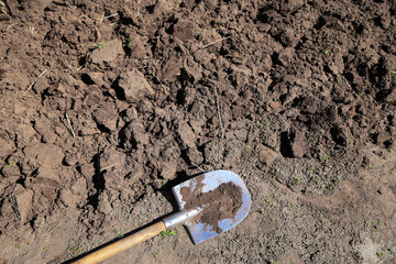 Digging up ground. Brown soil texture background with copyspace and shovel on garden bed in farm...