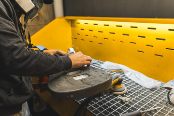 carbon fiber electric guitar body polishing process in the guitar factory, repairman with a mask. High quality photo