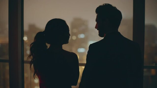 Romantic pair silhouettes embracing at evening window cityscape hotel back view