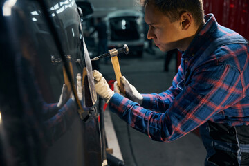 Skilled employer working with front fender in tire fitting