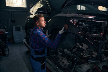 Young man installing fender on vehicle frame