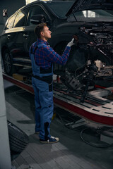 Young man installing fender on car frame