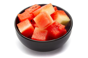 A black ceramic bowl filled with Organic watermelon (citrullus Lanatus) pieces. Isolated on a white...