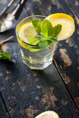 Cold Citrus Drink with Lemon and Mint on Dark Wooden Background, Copy Space