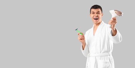Happy young man with photoepilator and razor on grey background with space for text