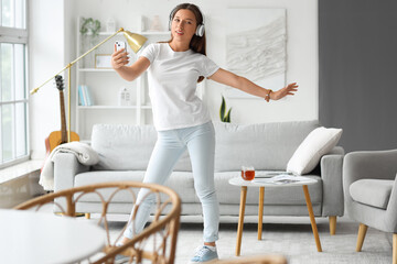 Young woman in headphones dancing on her day off at home