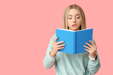Beautiful young thoughtful woman with book on pink background
