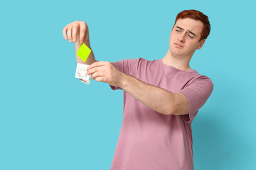 Emotional young man with condoms on blue background. Safe sex concept