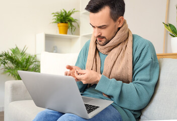 Ill young man taking pills while video chatting with doctor on laptop at home