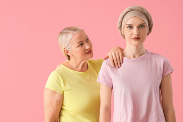 Young woman after chemotherapy with her mother on pink background. Stomach cancer concept