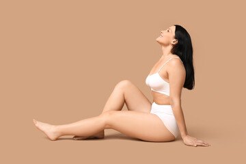 Fototapeta premium Body positive woman in underwear sitting on beige background