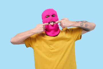 Handsome young man in balaclava posing on blue background